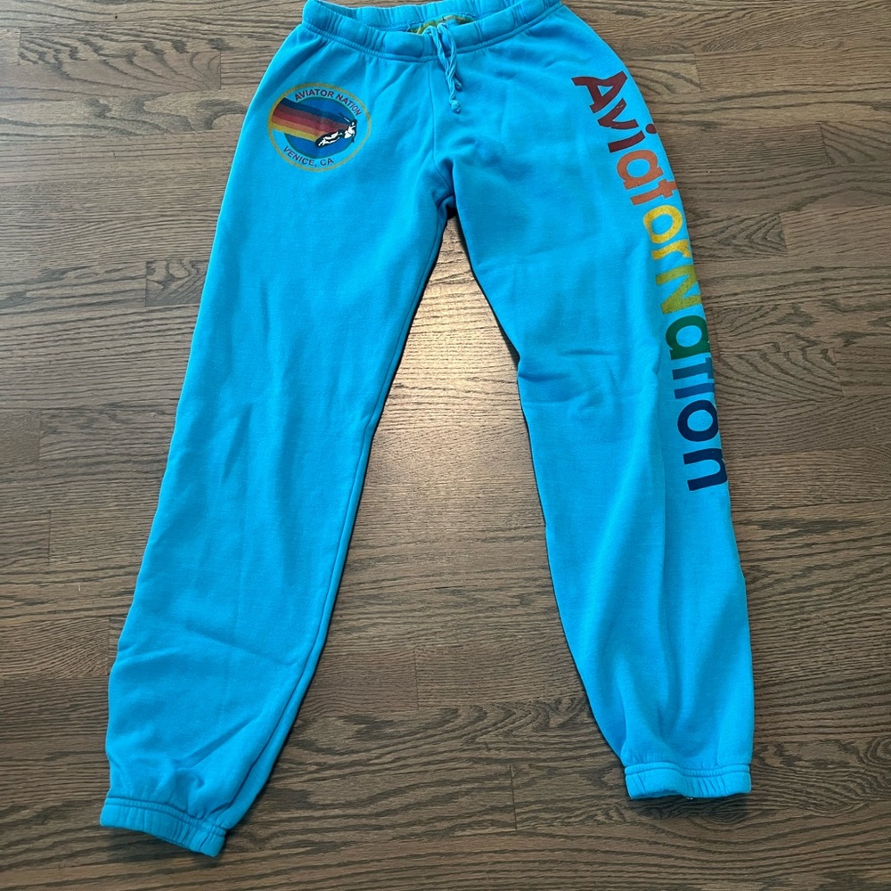 Aviator Nation sweatpants in Turquoise, on left side of Leg Brand spelled out.